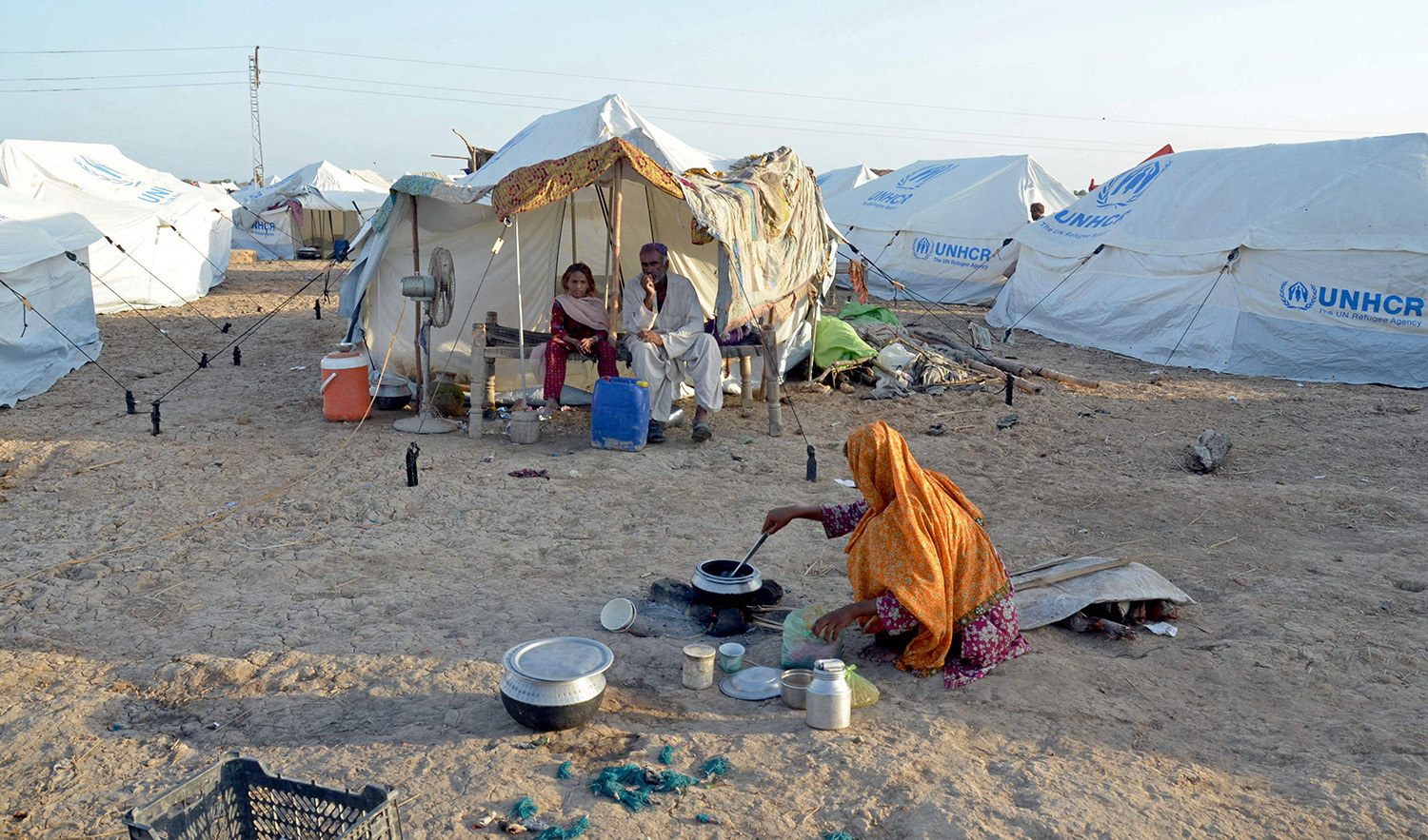A displaced flood-affected woman cooks food for her family at a makeshift camp at Sohbatpur in Jaffarabad district of Pakistan's Balochistan province on October 4, 2022. (AFP)