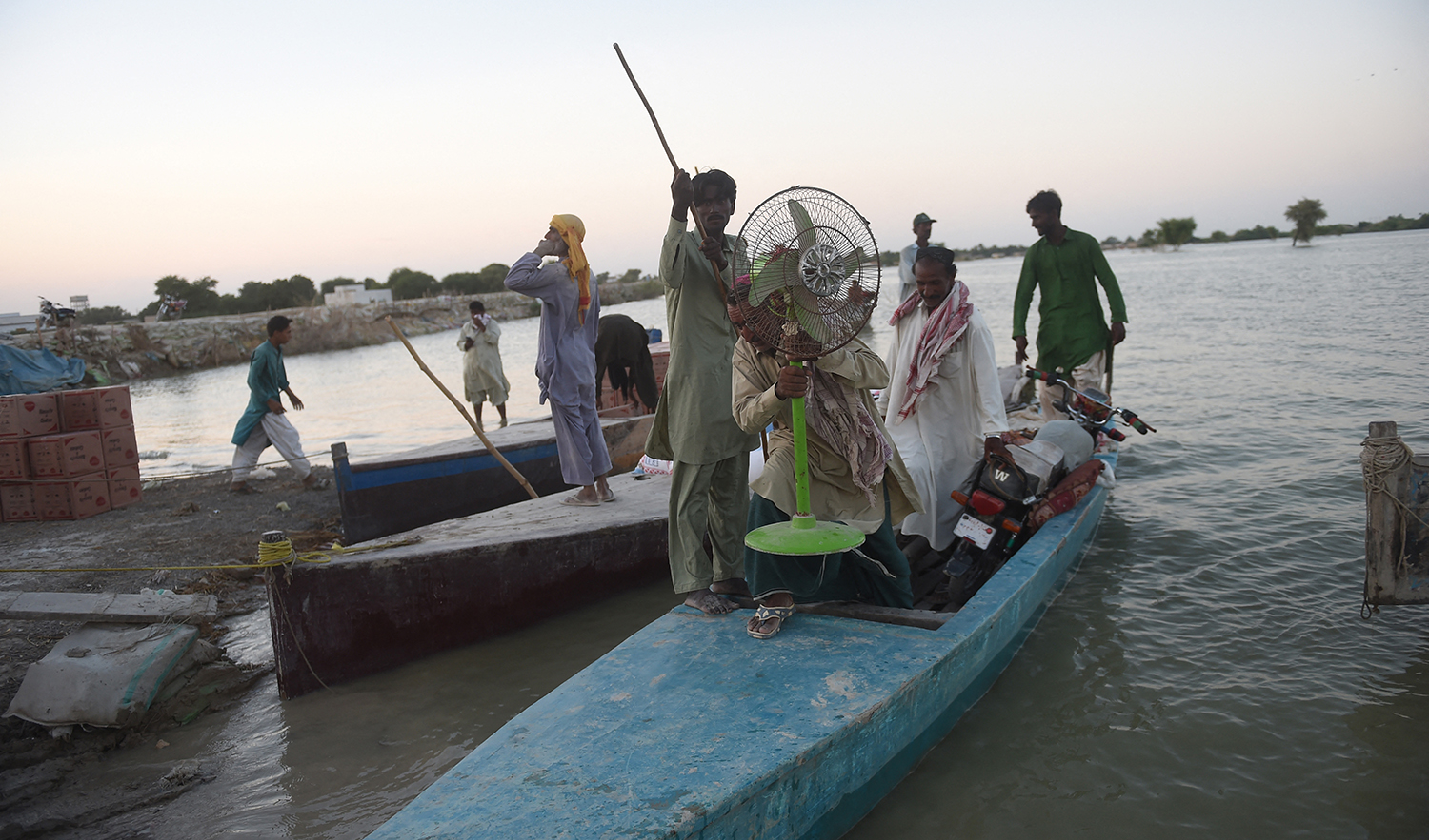 Internally displaced people use a boat to cross the flooded area in Dadu district of Pakistan's Sindh province on September 27, 2022. (AFP/File)