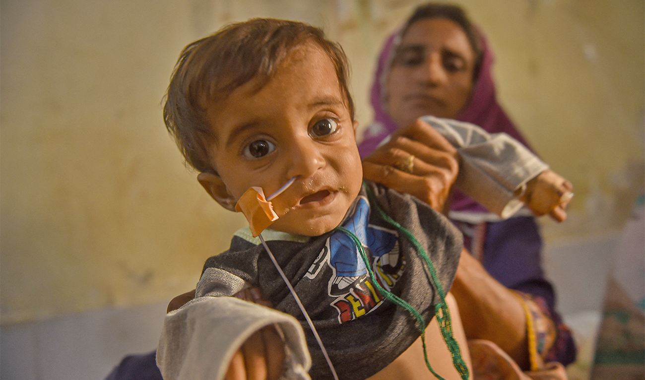An internally displaced flood-affected woman takes care of her sick child admitted in a hospital in Johi, Dadu district of Sindh province on September 27, 2022. (AFP)