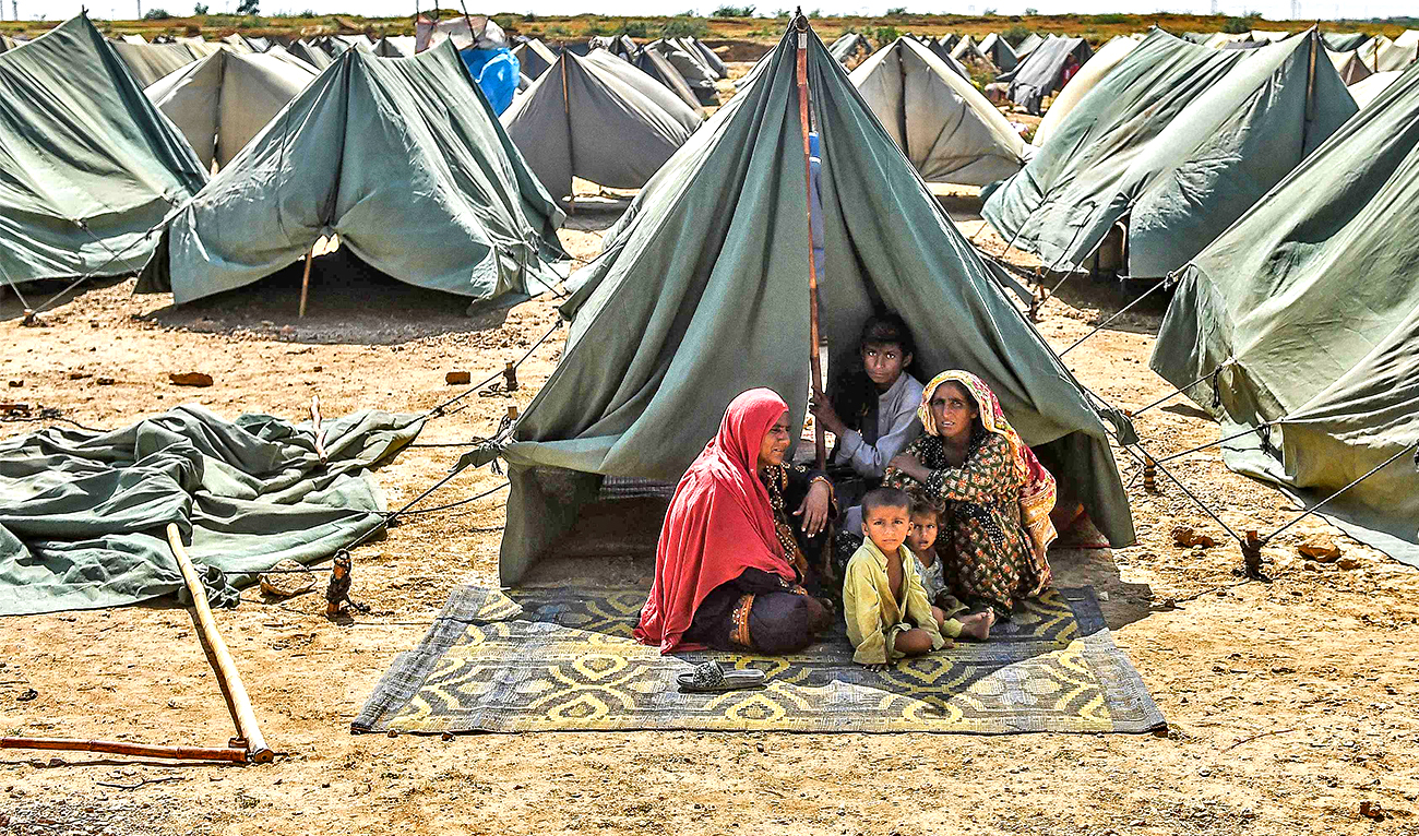 In this picture taken on September 28, 2022, an internally displaced flood-affected family sits outside their tent at a makeshift tent camp in Jamshoro district of Sindh province. (AFP)