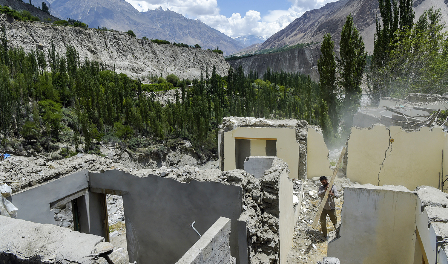 This representational file photo shows a resident clearing debris from a damaged house in Pakistan's Gilgit-Baltistan region on June 9, 2022. (AFP/File)