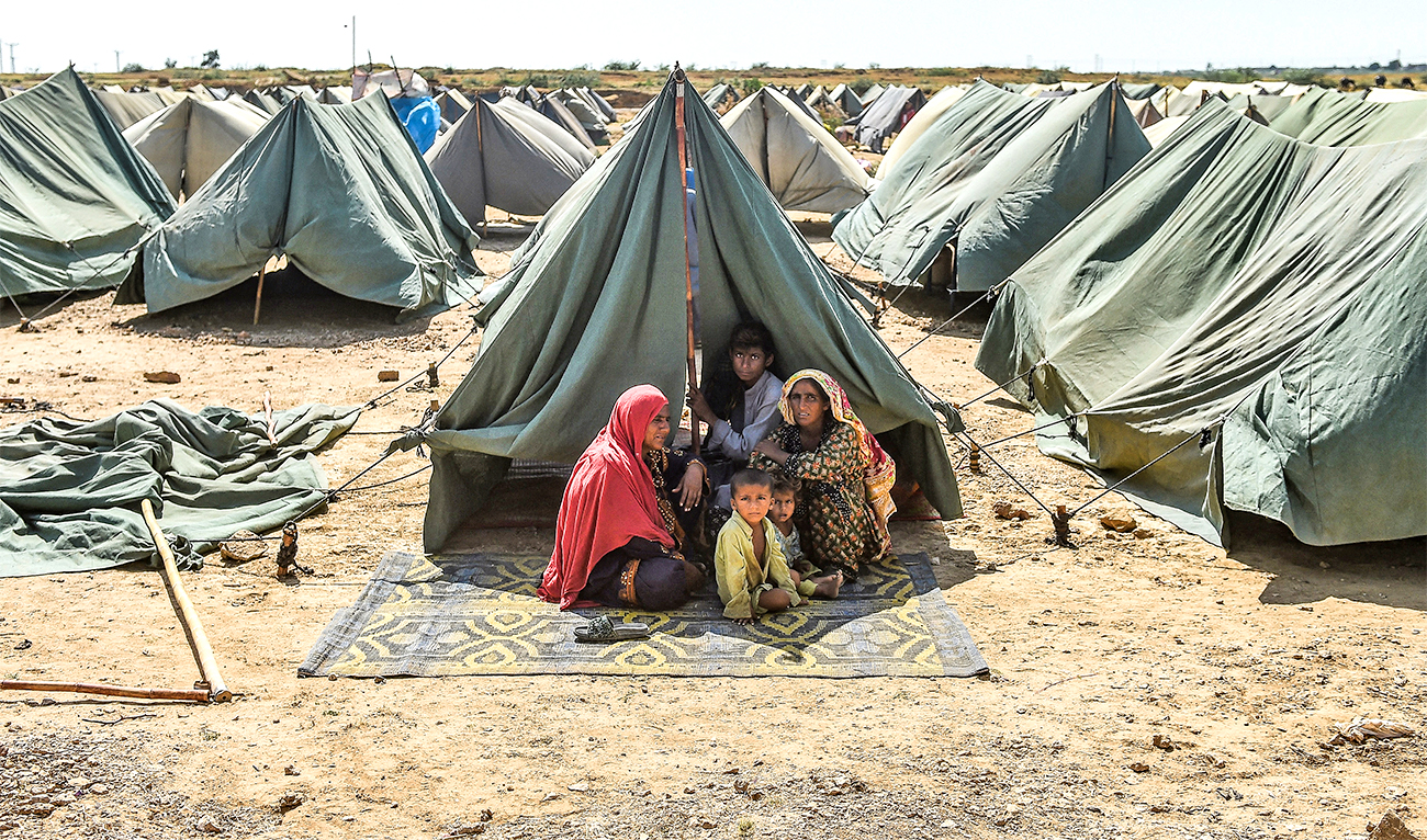 In this picture taken on September 28, 2022, an internally displaced flood-affected family sits outside their tent at a makeshift tent camp in Jamshoro district of Pakistan's Sindh province. (AFP)