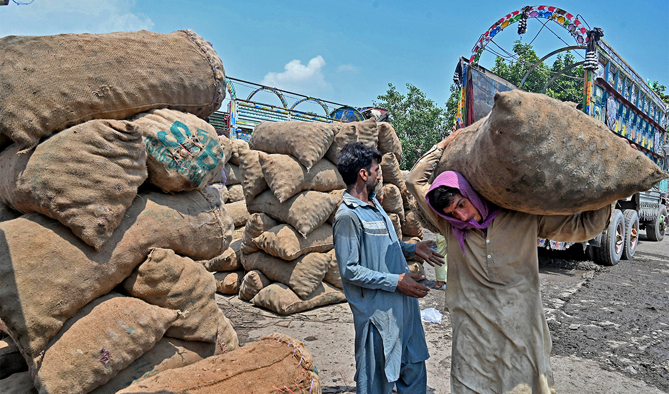 Labourers unload sacks of potatoes from a truck at a local market in Lahore on August 30, 2022. (AFP/File)