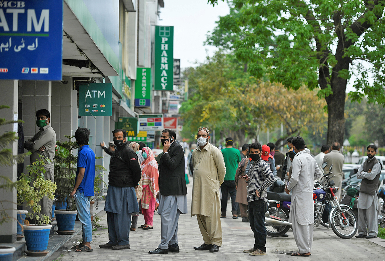 Residents wait for their turn to withdraw money outside a bank in Islamabad, Pakistan, on March 30, 2020. (AFP/File)