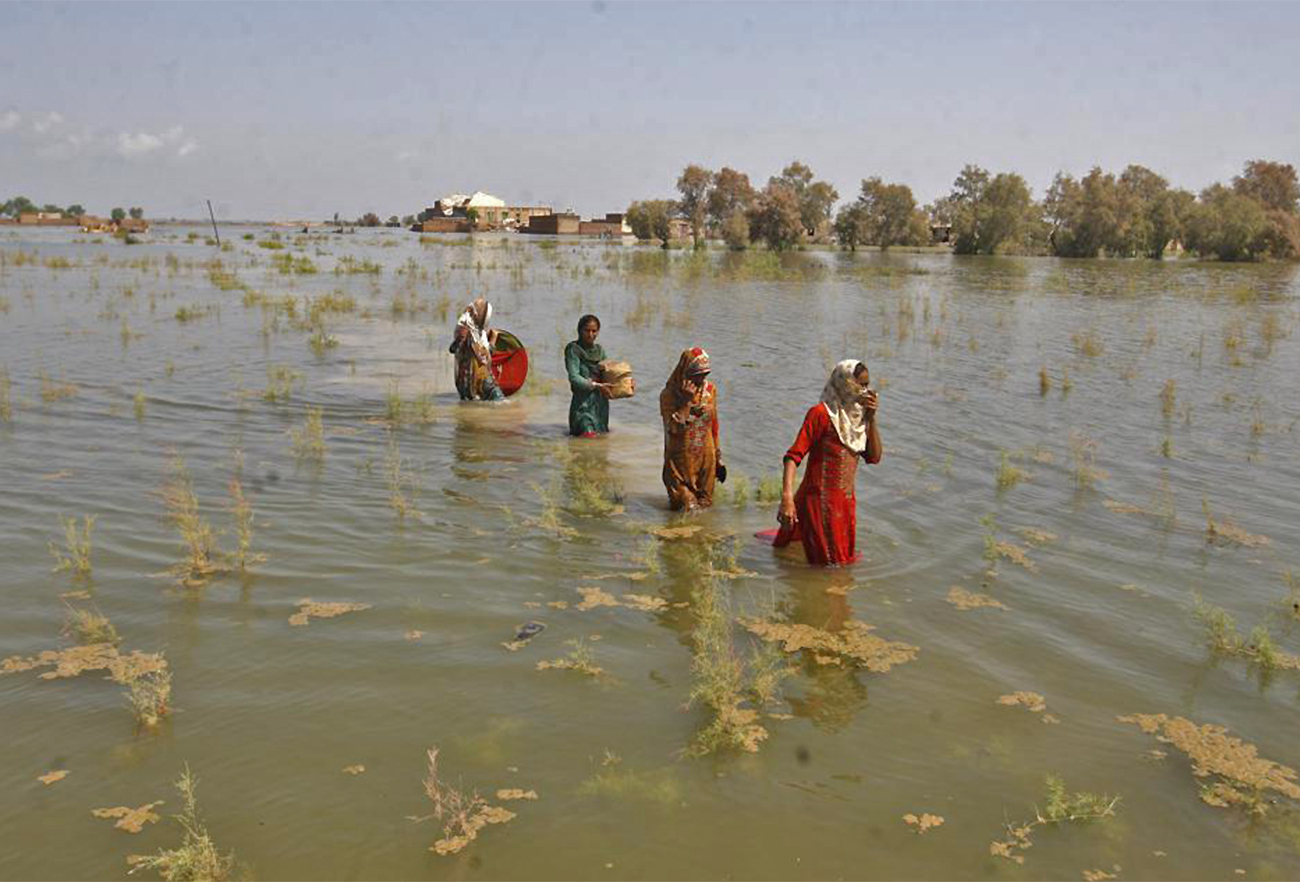Pakistani women wade through floodwaters as they take refuge in Shikarpur district of Sindh Province of Pakistan, on September 2, 2022. (AP)