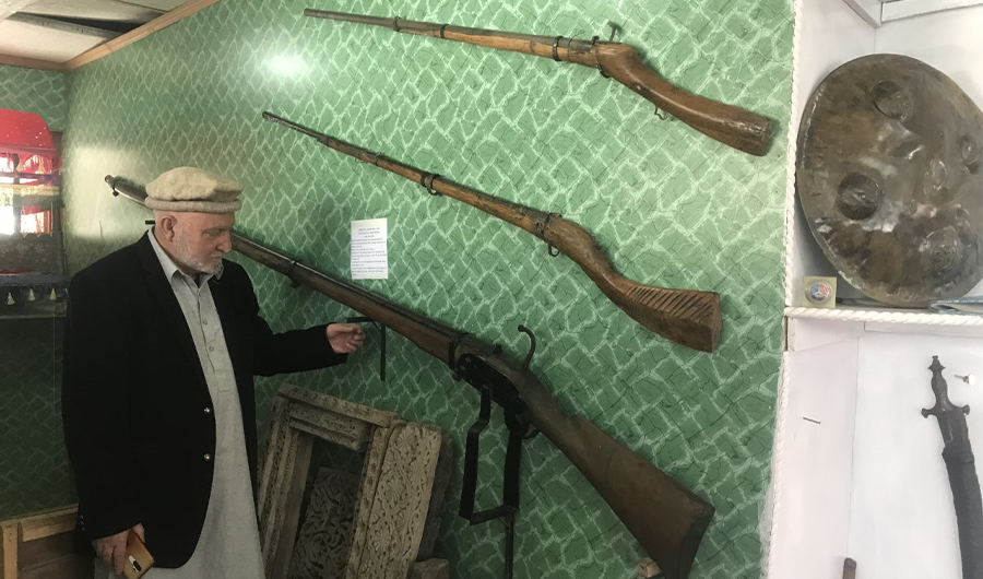 Dr. Hassan Khan Amacha poses for a photo in front of a 10-foot-long antique firearm at his museum in Shigar, Pakistan, on October 10, 2022. (AN Photo)