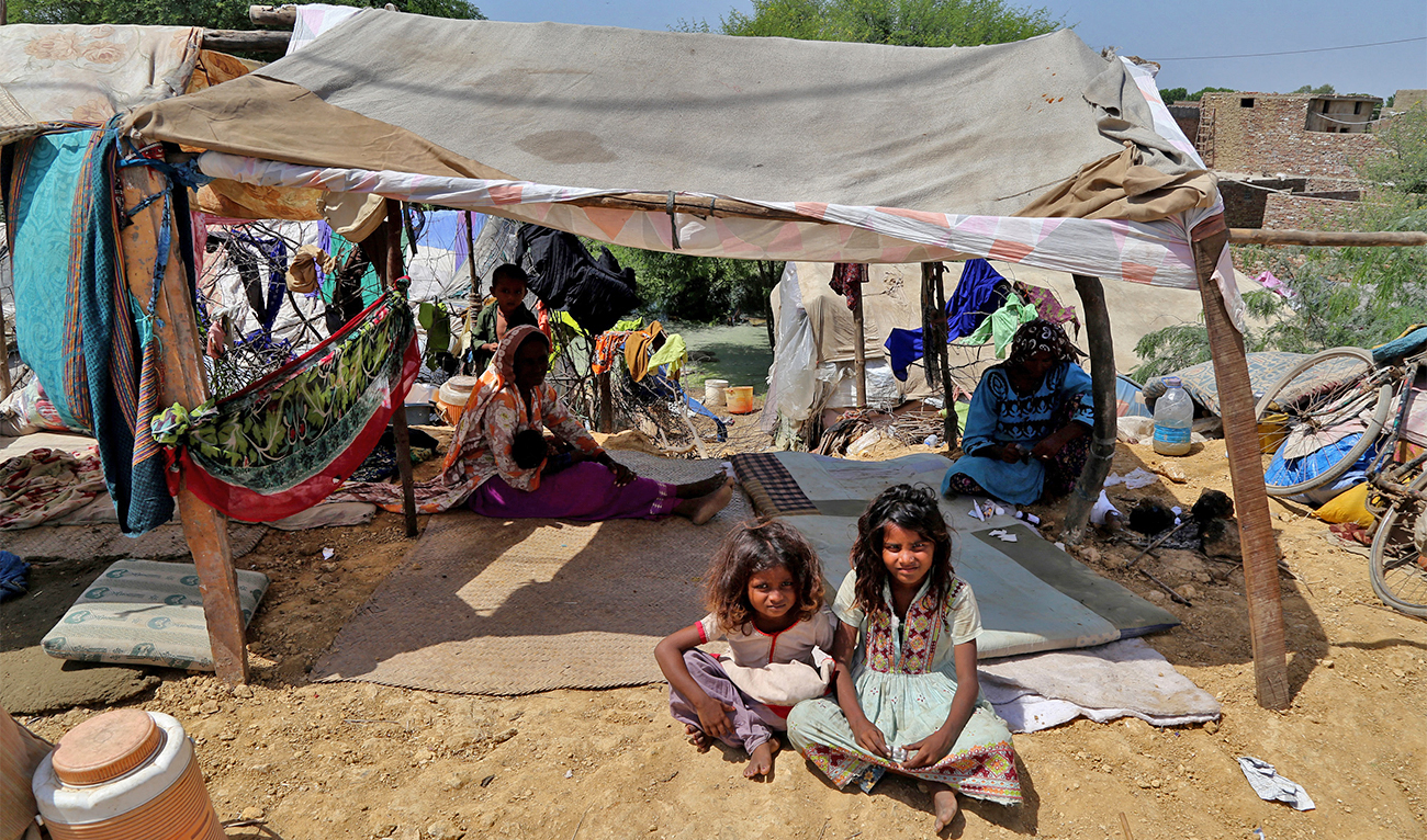 Internally displaced flood-affected people sit in a tent alongside flood waters after heavy monsoon rains in Hyderabad, Sindh province on September 6, 2022. (AFP)