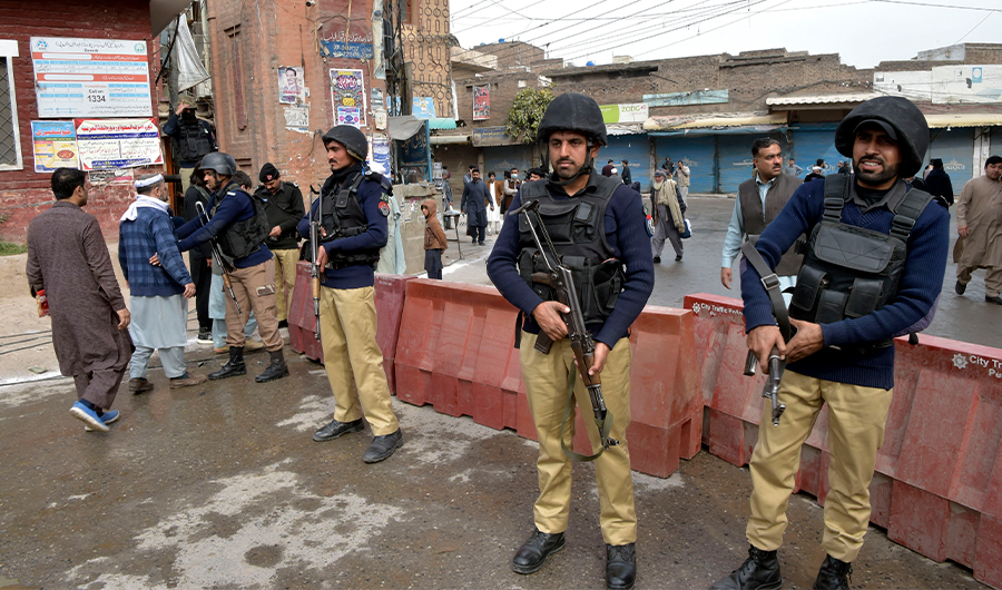 Policeman stand guard as mourners arrive to attend funeral prayers for bomb blast victims a day after a suicide attack in Peshawar on March 5, 2022. (AFP/FILE)