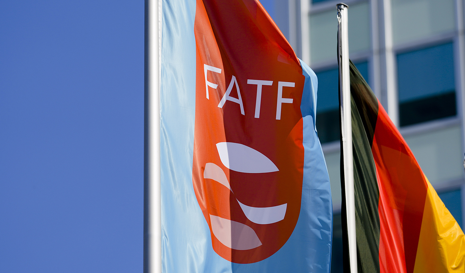 A flag with the logo of the Financial Action Task Force, FATF, waves in the wind next to the German national flag during a meeting of the task force at the Congress Center in Berlin, Germany, on June 17, 2022. (AP/File)