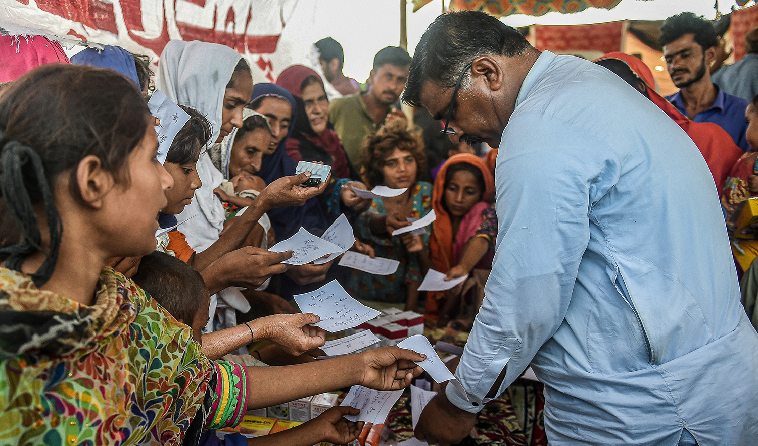 Internally displaced flood-affected people hold out their doctor’s prescriptions to get medicine at a medical camp set up for the flood affected in Jamshoro district of Pakistan's Sindh province on September 27, 2022. (AFP/File)