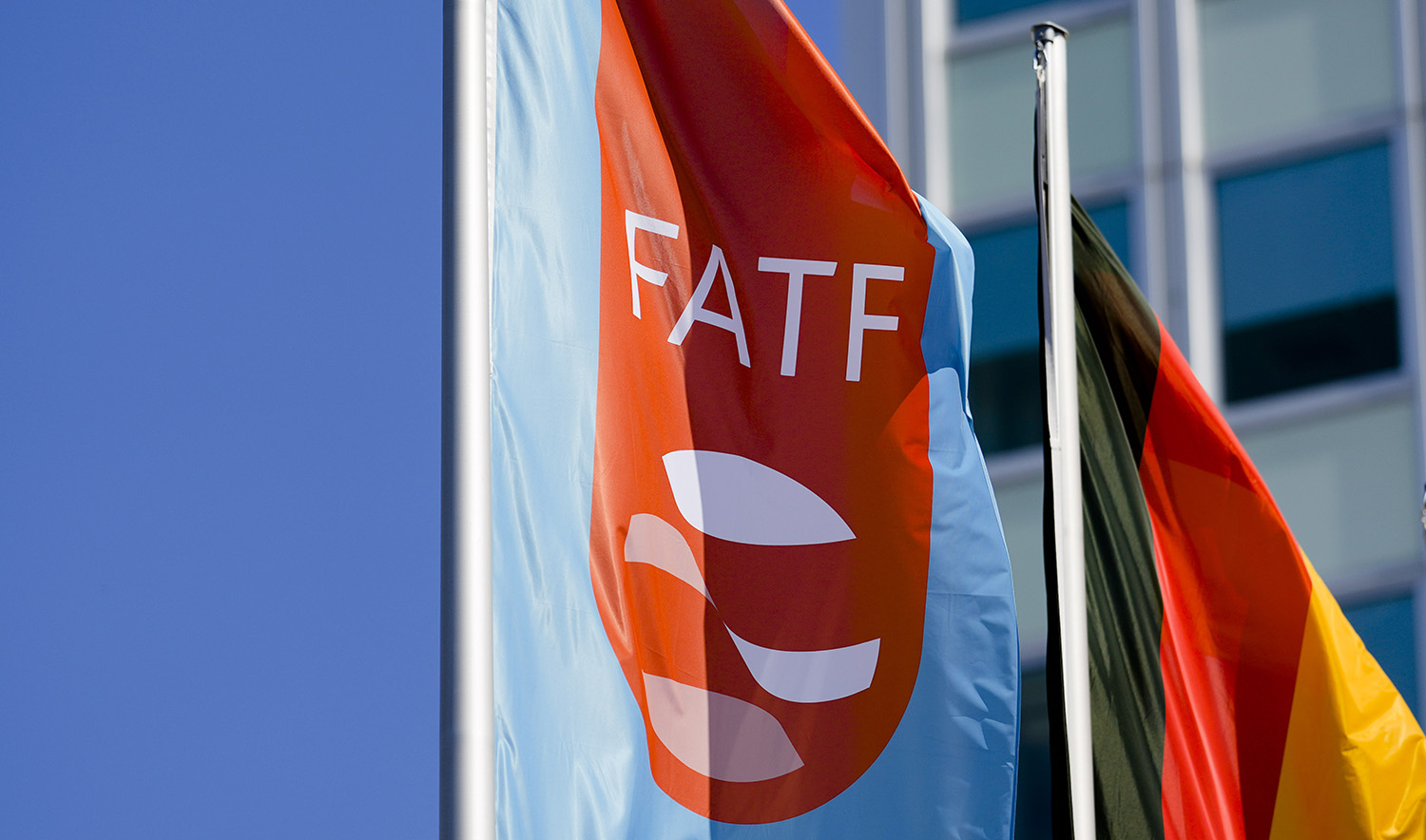 A flag with the logo of the Financial Action Task Force, FATF, waves in the wind next to the German national flag during a meeting of the task force at the Congress Center in Berlin, Germany, on June 17, 2022. (AP)