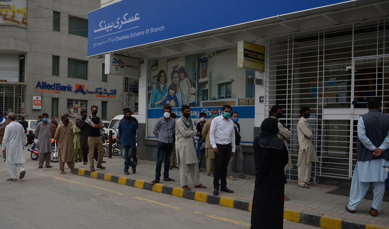 Pakistani people line up to pay utility bills outside a bank in Rawalpindi on March 30, 2020. (AFP/File)