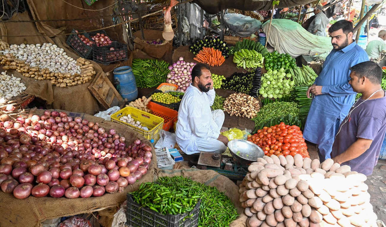 People buy vegetables at a local market in Lahore on August 29, 2022. (AFP/File)