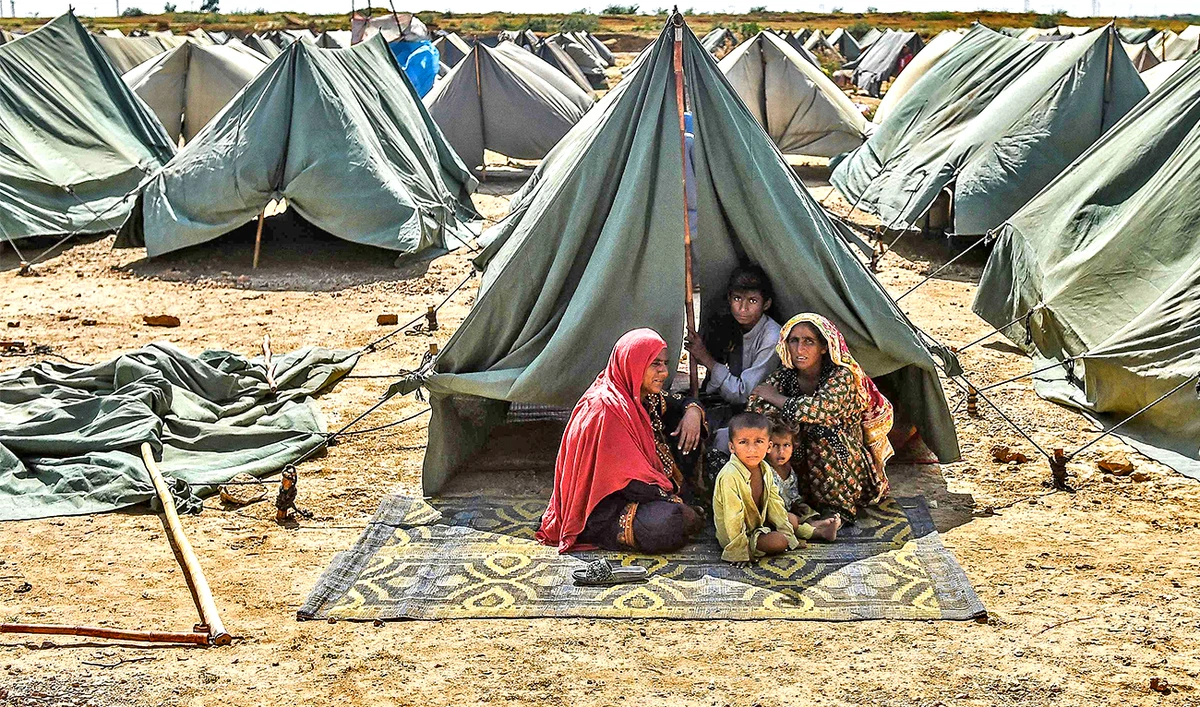 In this picture taken on September 28, 2022, an internally displaced flood-affected family sits outside their tent at a makeshift tent camp in Jamshoro district of Sindh province. (AFP)