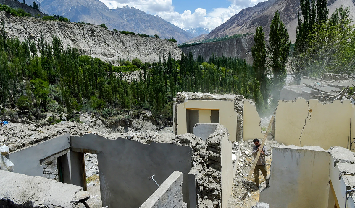 This representational file photo shows a resident clearing debris from a damaged house in Pakistan's Gilgit-Baltistan region on June 9, 2022. (AFP/File)