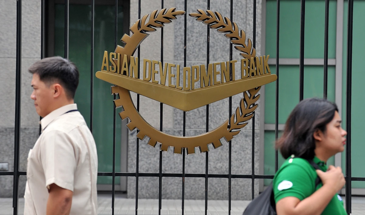 In this file photo, pedestrians walk past a logo of the Asian Development Bank (ADB) displayed outside its headquarters in Manila on Sept. 2, 2010. (AFP)