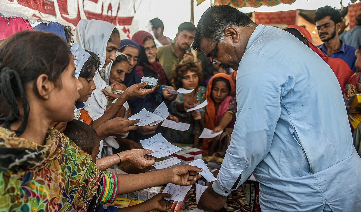 Internally displaced flood-affected people hold out their doctor’s prescriptions to get medicine at a medical camp set up for the flood affected in Jamshoro district of Pakistan's Sindh province on September 27, 2022. (AFP/File)