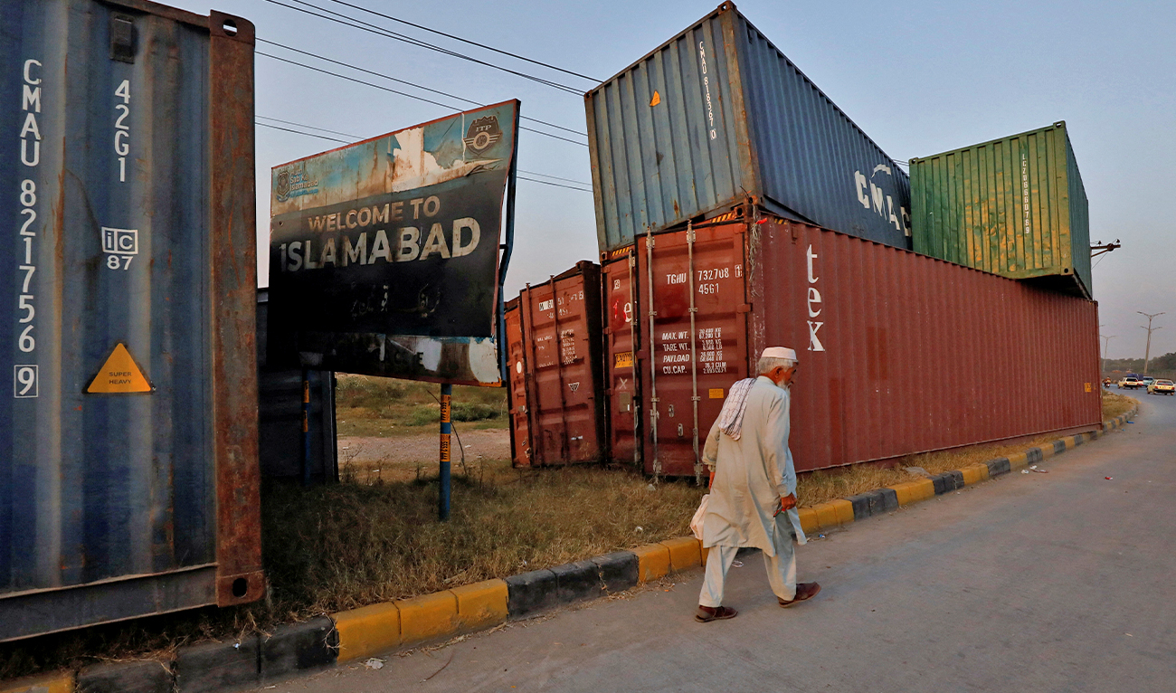 A man walks past shipping containers used to block the area, seen ahead of the planned freedom march by former Prime Minister Imran Khan to pressure the government to announce new elections, in Islamabad, Pakistan, on November 2, 2022. (REUTERS)