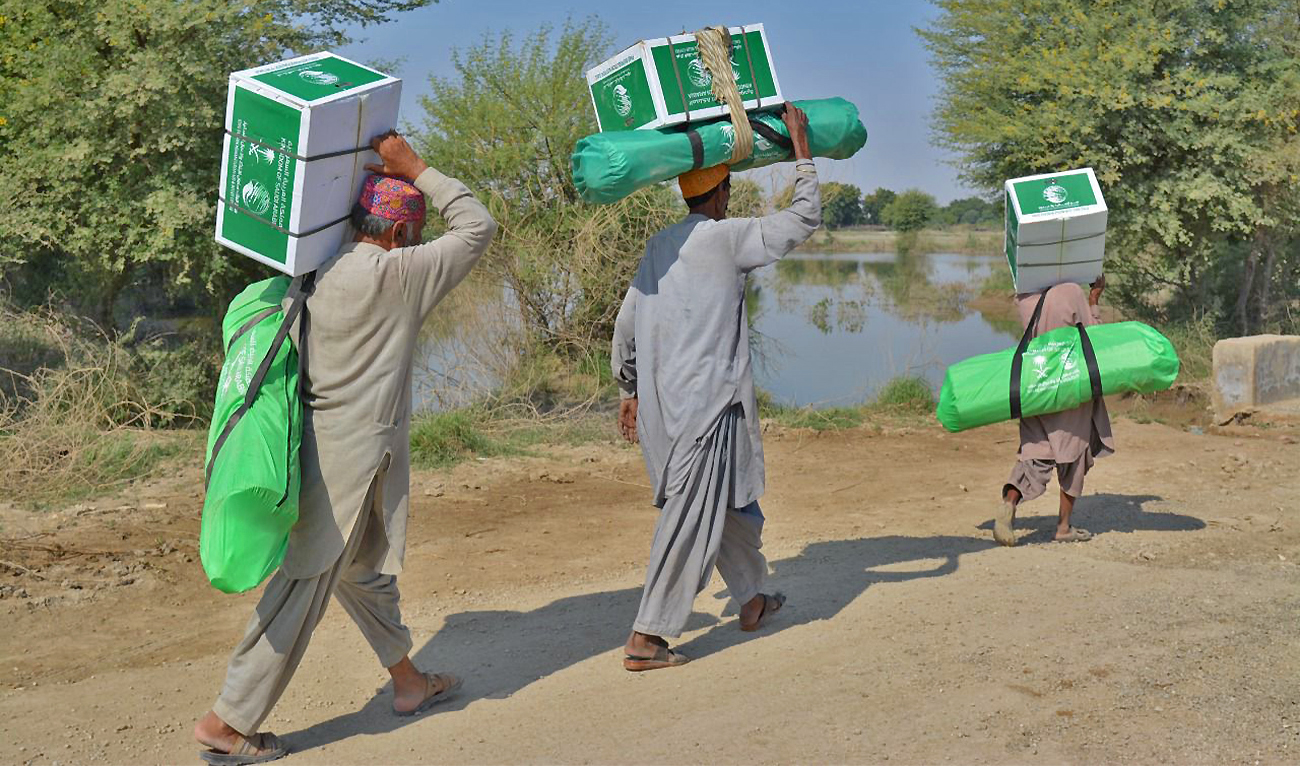 The picture shared by KSrelief on October 30, 2022 shows flood affectees carrying aid distributed by Saudi Arabia’s King Salman Humanitarian Aid and Relief Center in Pakistan. (KSrelief)