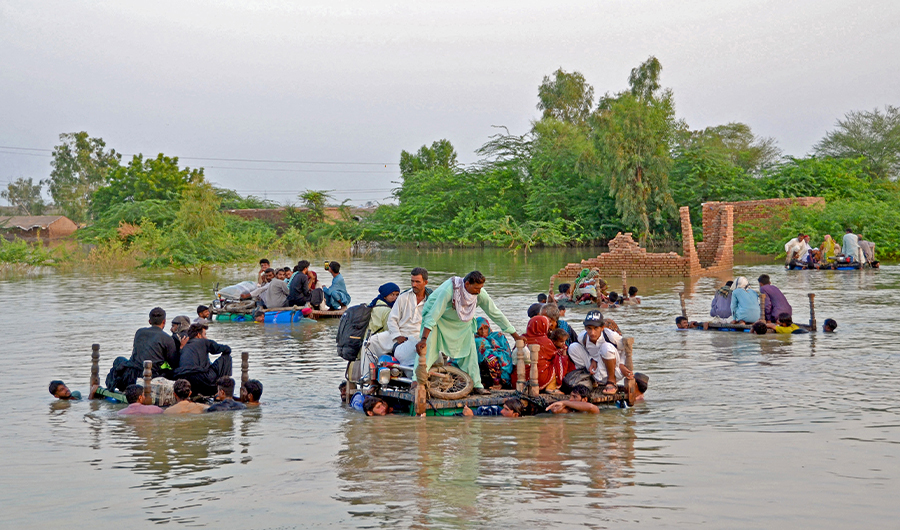 Internally displaced people wade through floodwaters after heavy monsoon rains in Jaffarabad district in Balochistan province on September 8, 2022. (AFP/FILE)