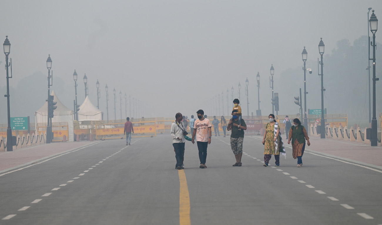Pedestrians walk along a road near the India Gate amid heavy smog in New Delhi on November 3, 2022. (Photo courtesy: AFP)
