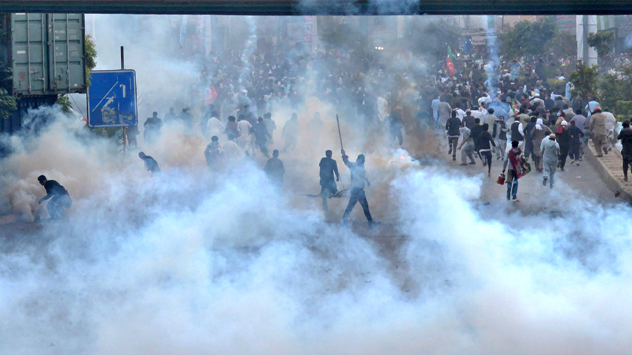 Supporters of former Pakistani Prime Minister Imran Khan's party, 'Pakistan Tehreek-e-Insaf' run for cover after police fire tear gas shell during a protest to condemn a shooting incident on their leader's convoy, in Rawalpindi, Pakistan, on November 4, 2022. (AP)