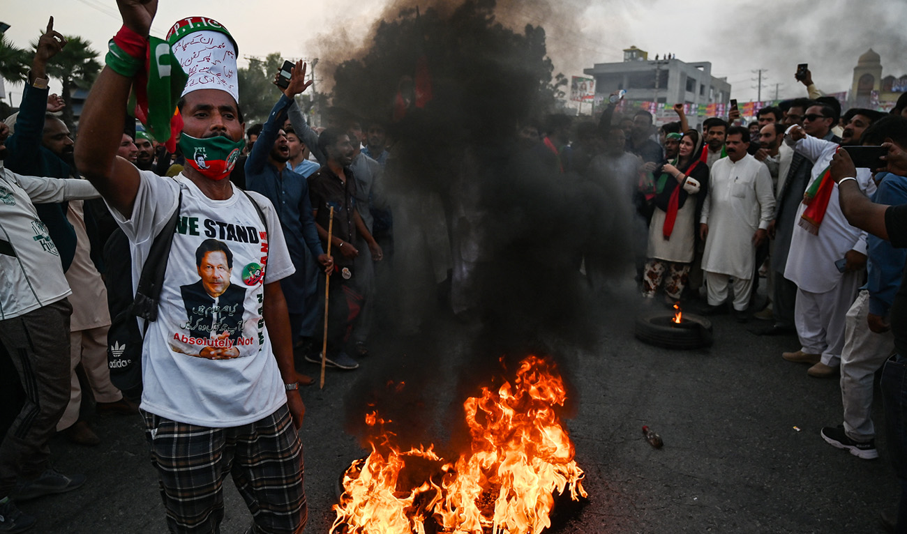 Supporters of former Pakistani prime minister Imran Khan, shout slogans beside burning tyres as they block the main highway near the container truck a day after the assassination attempt on Khan, at the cordoned-off site of a gun attack in Wazirabad on November 4, 2022. (AFP)