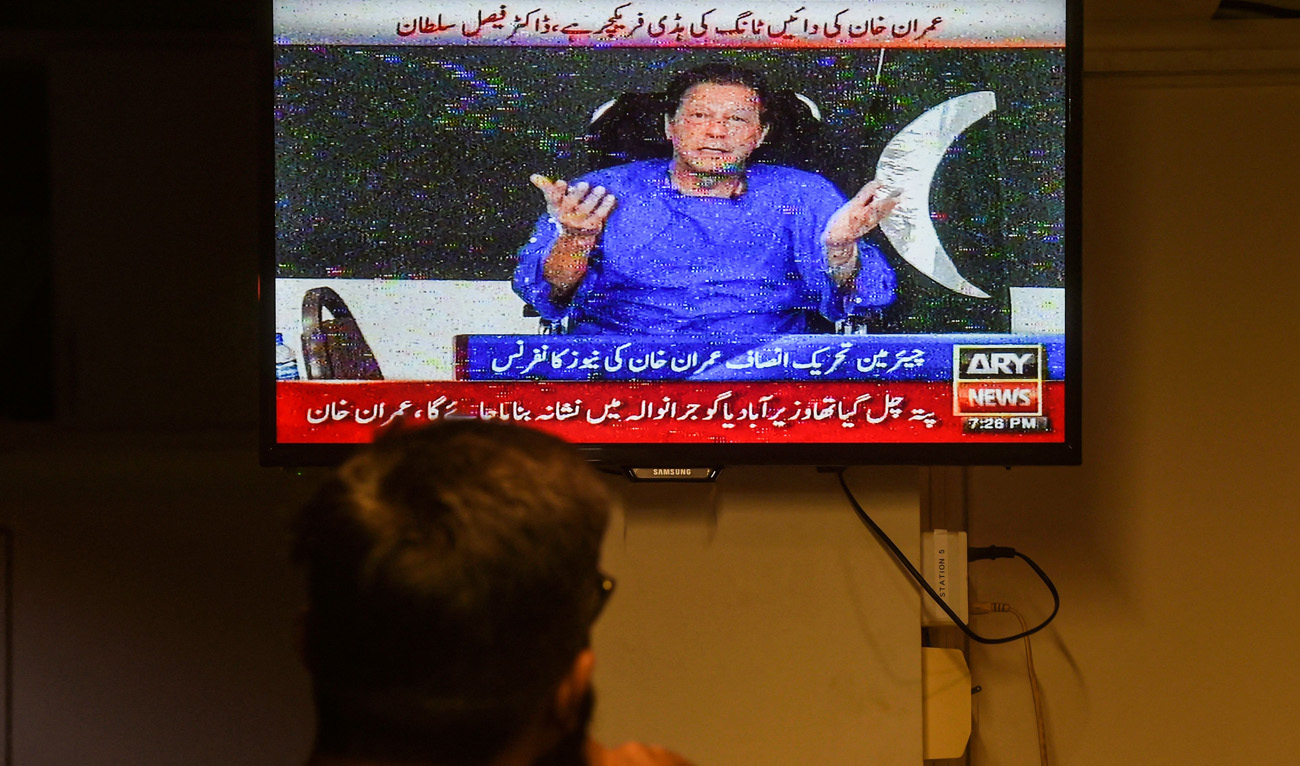A man watches a television channel broadcasting the address of Pakistani former prime minister Imran Khan a day after an assassination attempt during his long march near Wazirabad, in Karachi on November 4, 2022. (AFP)