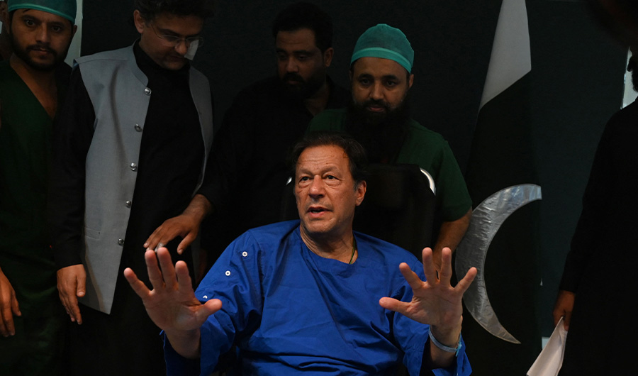 Pakistani paramedics move Pakistan's former prime minister Imran Khan as he sits in a wheelchair, after speaking to media representatives at a hospital in Lahore on November 4, 2022, (AFP)
