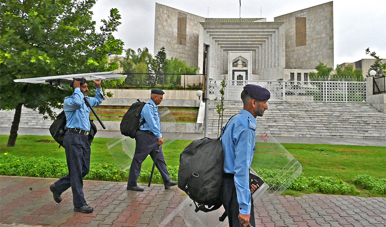 Riot policemen carry their gear as they walk past the Supreme Court building in Islamabad, Pakistan, on July 25, 2022. (AFP/File)