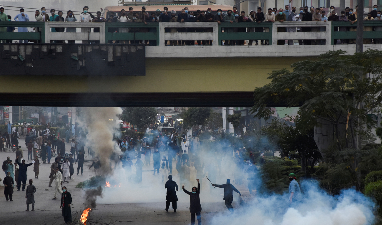 People react as they protest amid tear gas smokes used to disperse them during a protest to condemn the shooting incident on a long march held by Pakistan's former Prime Minister Imran Khan in Wazirabad, in Rawalpindi, Pakistan November 4, 2022. (REUTERS)