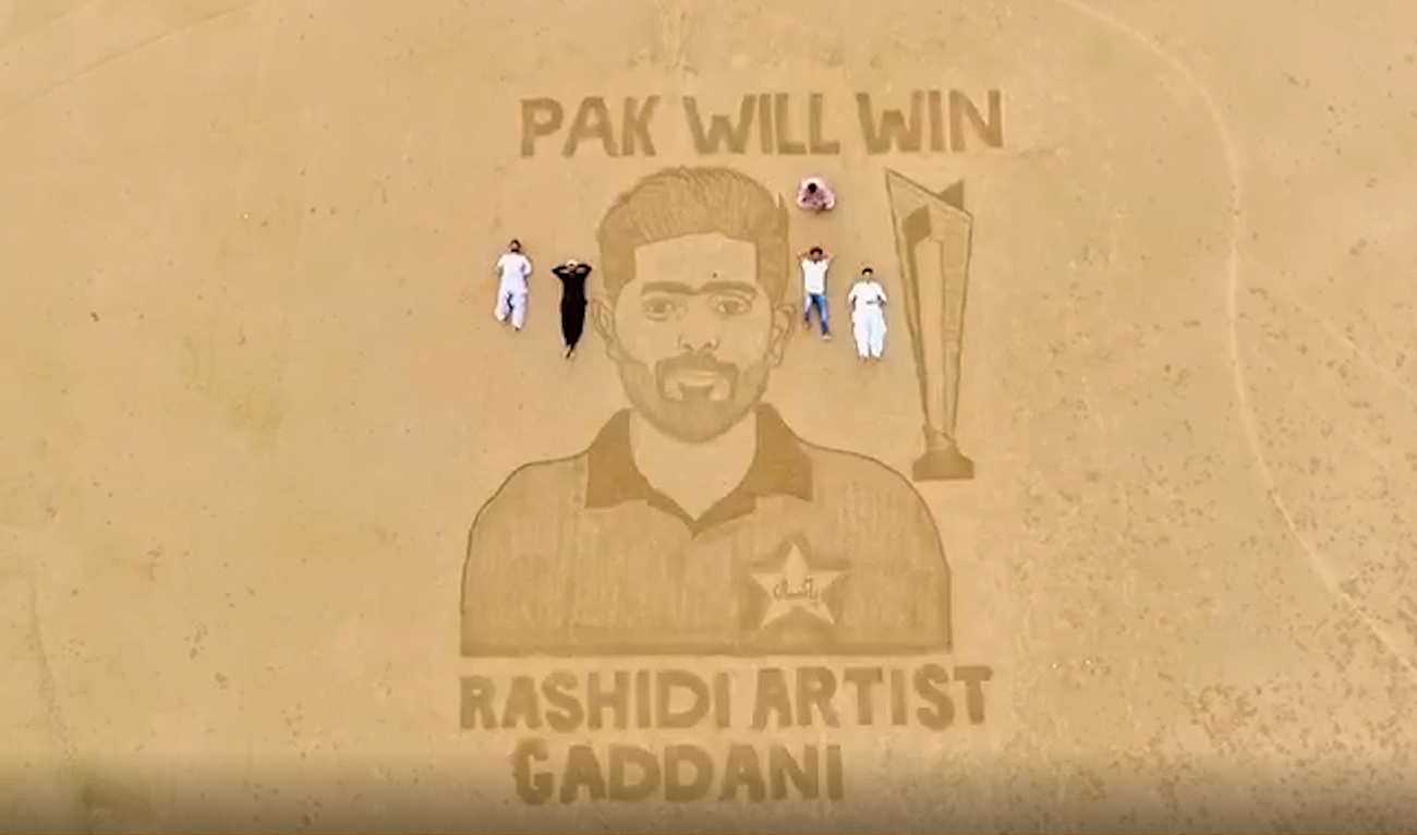 An overview shows Pakistan's Rashidi Artists Gaddani group as they created a large sand drawing on Gaddani beach in Balochistan province depicting Pakistani cricket captain Babar Azam and T20 World Cup trophy on November 8, 2022. (AN Photo)