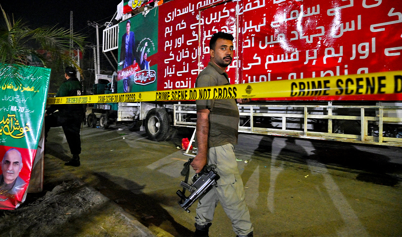 A police officer stands guard in front of container truck used by the former Pakistani prime minister Imran Khan during his political rallies, hours after a gun attack in Wazirabad, Pakistan, on November 3, 2022. (FP)