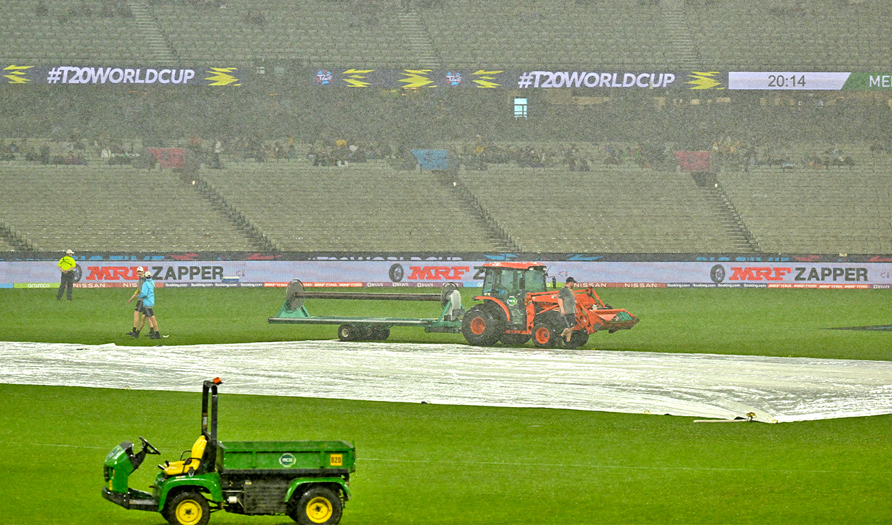 Ground staff cover the field as rain delays the start of play during the ICC men's Twenty20 World Cup 2022 cricket match between New Zealand and Afghanistan at Melbourne Cricket Ground (MCG) on October 26, 2022 in Melbourne. (AFP)