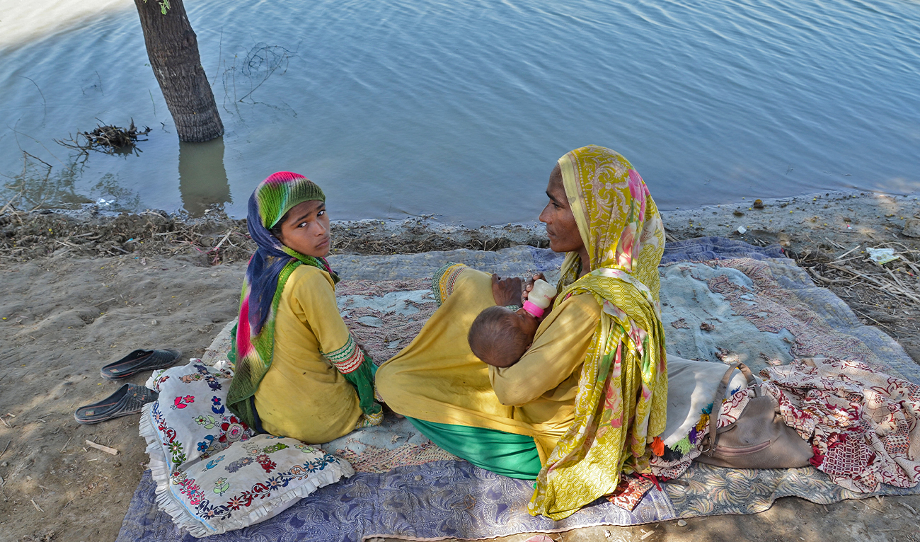 An internally displaced flood-affected woman feeds her child alongside flood water at a makeshift camp in Jaffarabad, Balochistan province on September 23, 2022. (AFP/File)