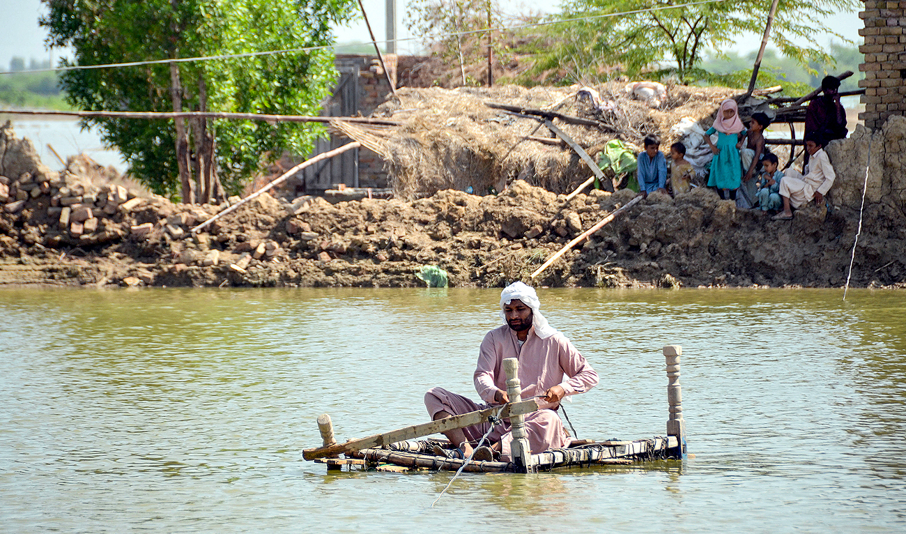 In this picture taken on September 28, 2022, an internally displaced flood-affected family sits outside their tent at a makeshift tent camp in Jamshoro district of Sindh province. (Photo courtesy: AFP/File)
