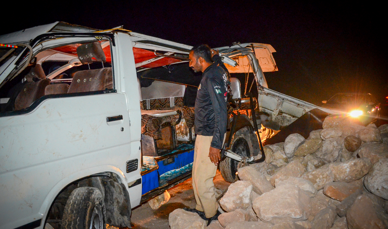 A policeman stands beside a damaged passenger mini bus after an overnight accident in Sehwan of Sindh province on November 18, 2022. (Photo courtesy: AFP)
