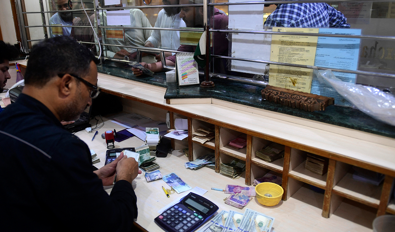 People exchange foreign currency at a shop in Karachi on April 7, 2022. (Photo courtesy: AFP/File)