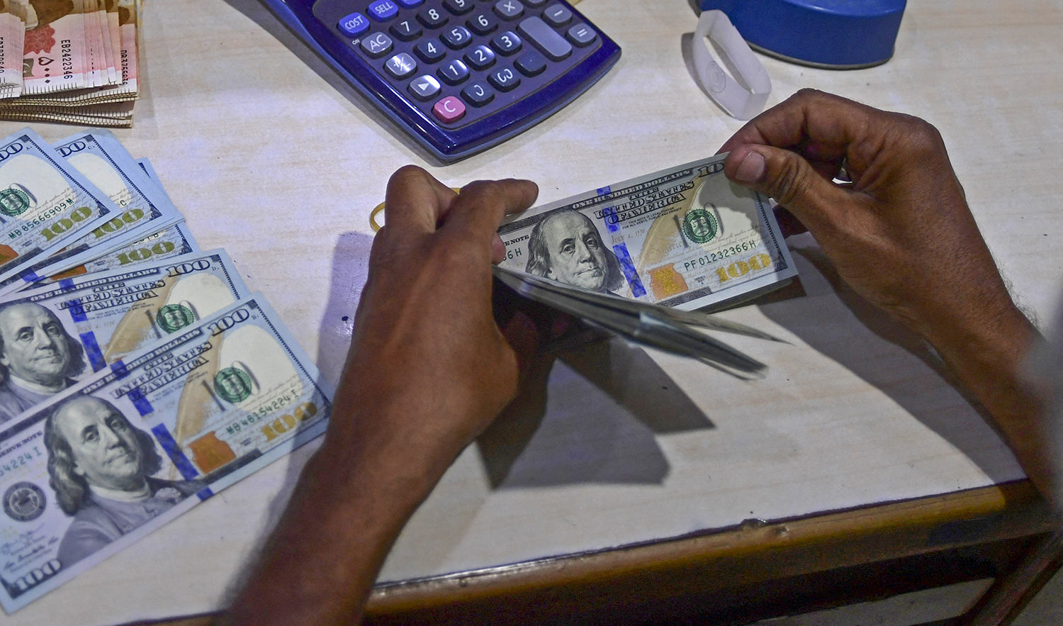 A foreign currency dealer counts US dollar notes at a currency market in Karachi, Pakistan, on July 19, 2022. (AFP/File)