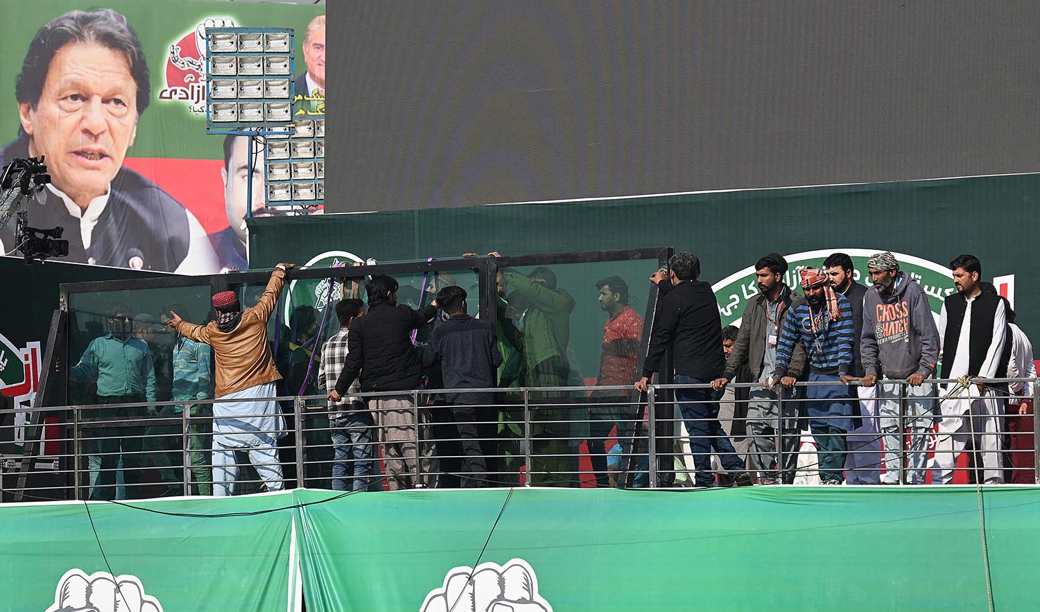 Workers install a bullet proof glass shield on the main stage of the venue ahead of the start an anti-government rally lead by former Prime Minister Imran Khan (not pictured) in Rawalpindi on November 26, 2022. (AFP)