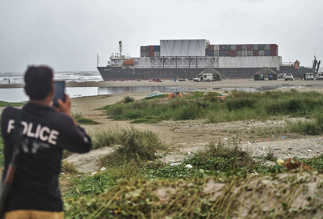 A policeman takes pictures with his mobile phone of a cargo ship docked at the Sea View beach, in Karachi, Pakistan on July 24, 2021. (AFP/File)