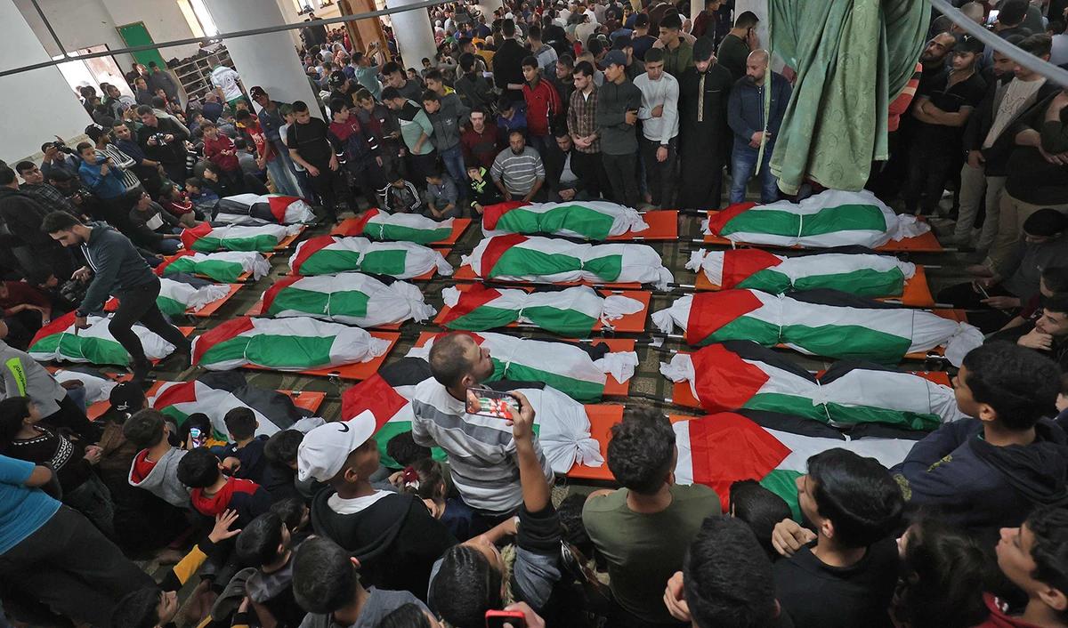 Palestinians carry the flag-draped bodies of people who died a day earlier, when fire broke out in an apartment, in the Jabalia refugee camp in the northern Gaza strip, on November 18, 2022. (AFP)