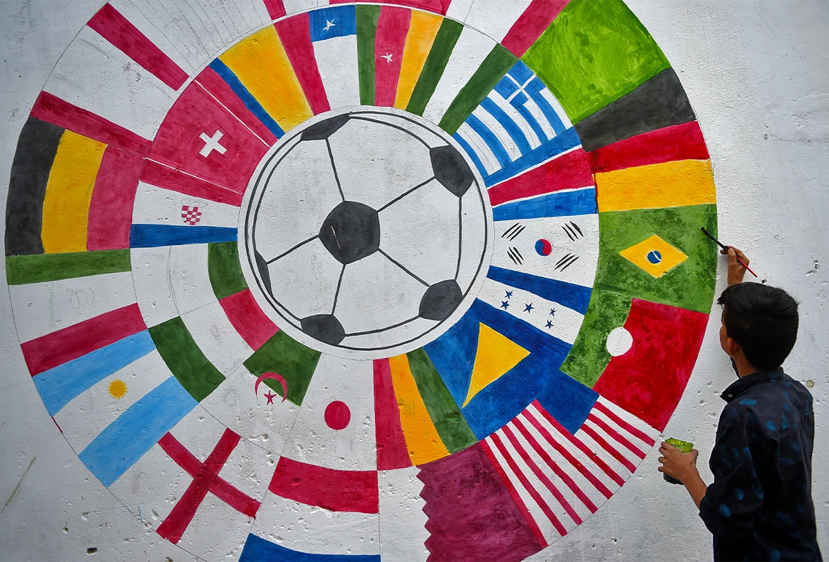 In this picture taken on November 7, 2022, a Pakistani soccer fan paints a wall mural of participating countries of the Qatar 2022 FIFA World Cup football tournament, along a street in Karachi. (AFP)