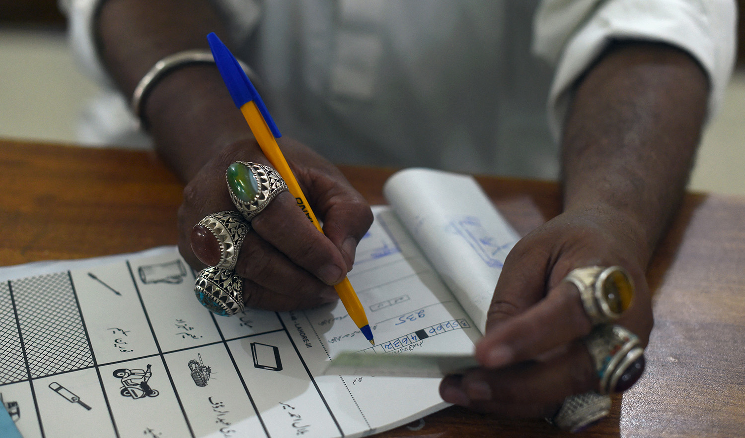 A election official man notes down information of an ID of a voter during Pakistan's general election at a polling station in Lahore on July 25, 2018. (AFP/File)
