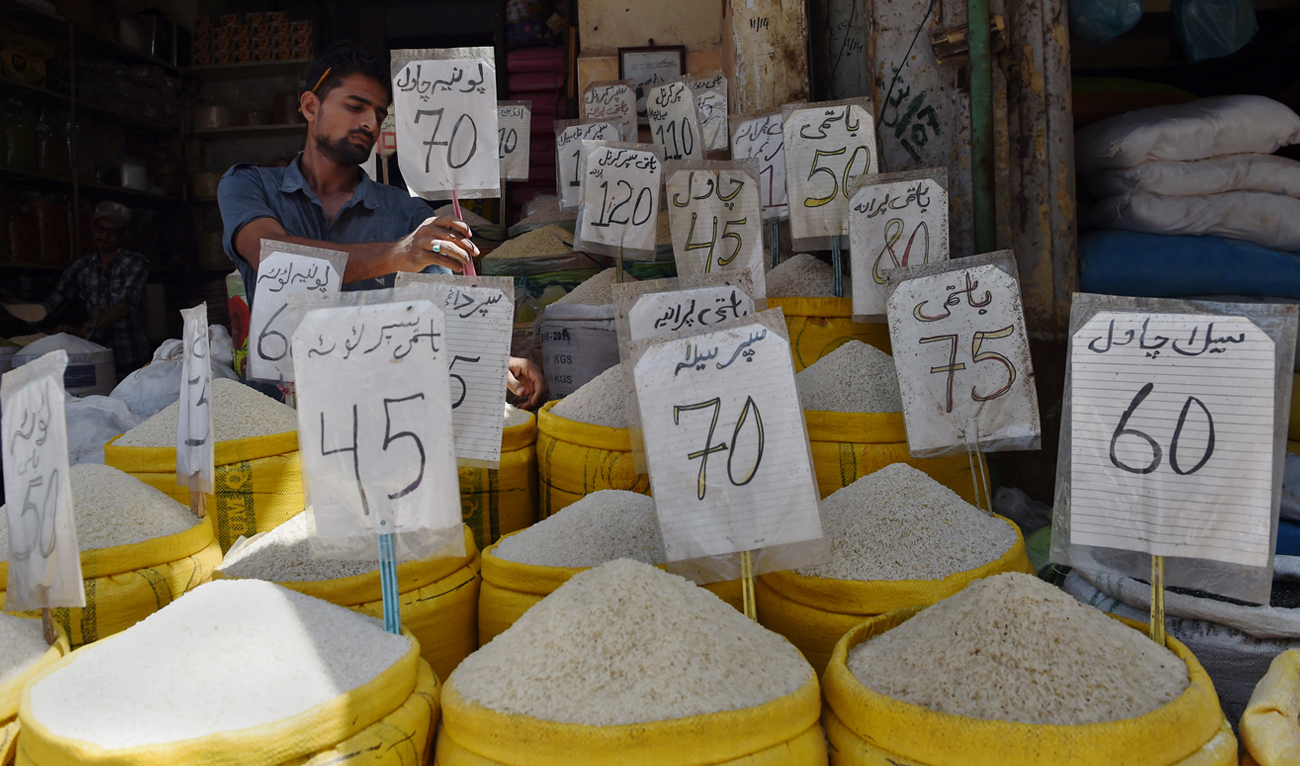 A Pakistani shopkeeper attaches rate cards on sacks of rice at the main wholesale market in Karachi on June 1, 2016. (Photo courtesy: AFP/File)