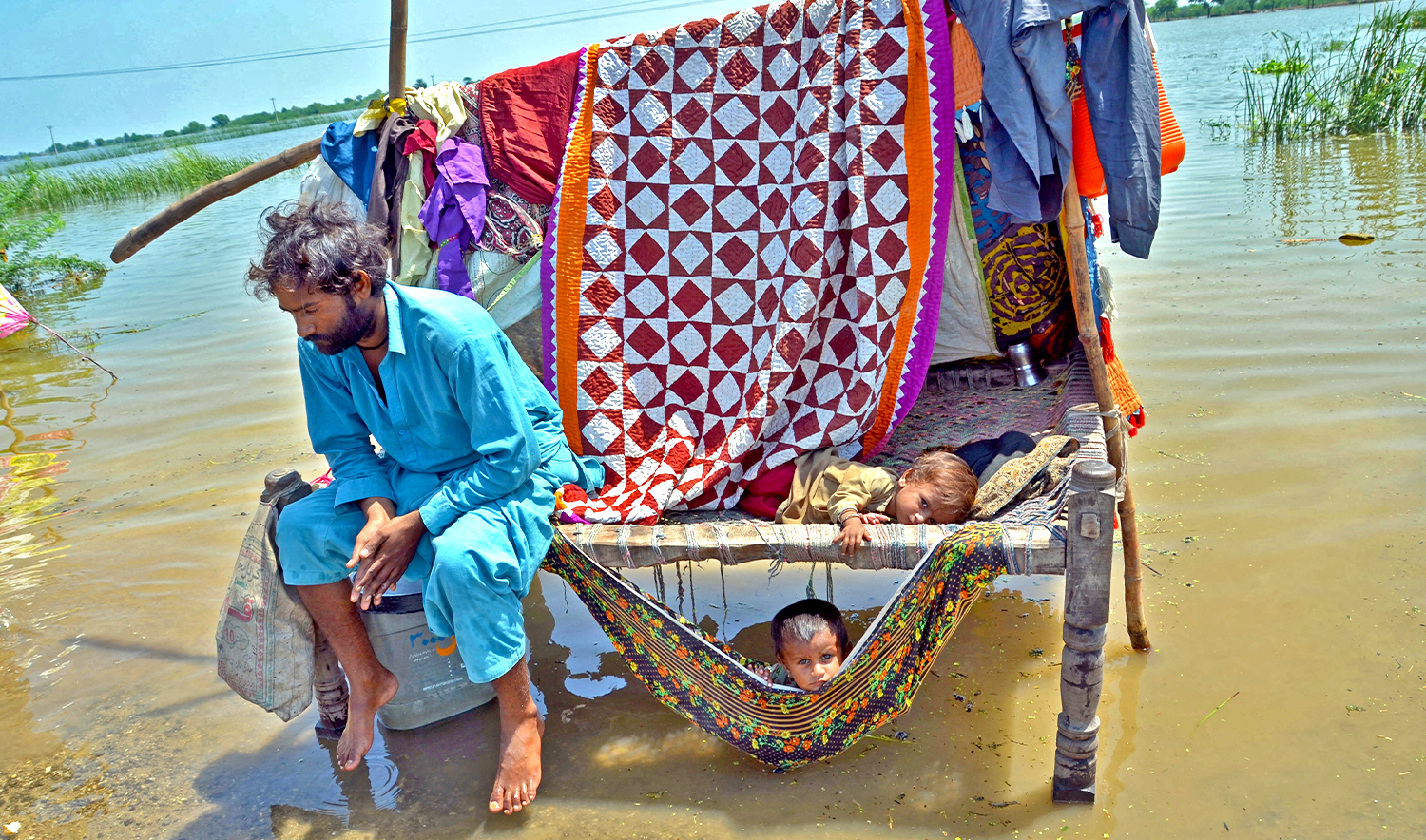 A flood-affected man sits along with his children alongside flood waters after heavy monsoon rains in Jaffarabad district of Balochistan province on August 31, 2022. (AFP/File)