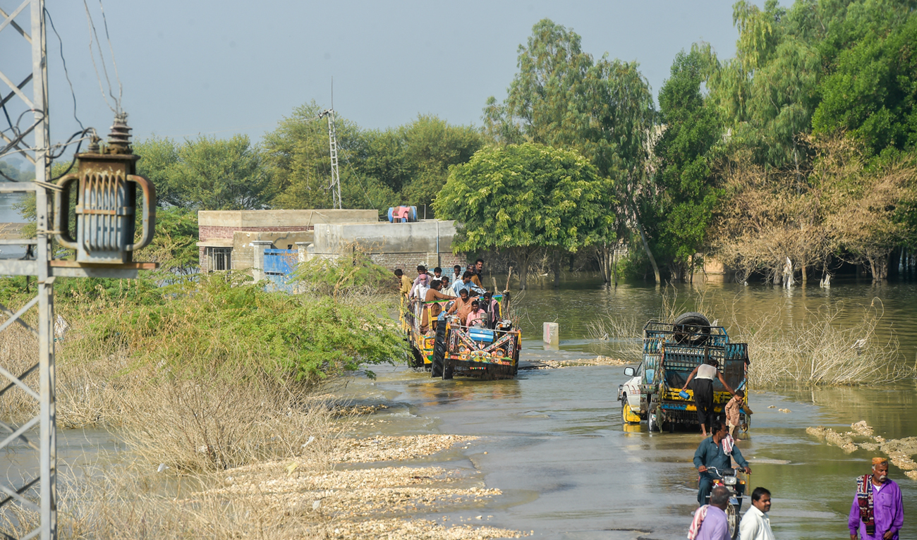 In this picture taken on October 28, 2022, internally displaced people use tractor trolley to wade across a flooded street in Dadu district of Sindh province. (Photo courtesy: AFP/File)