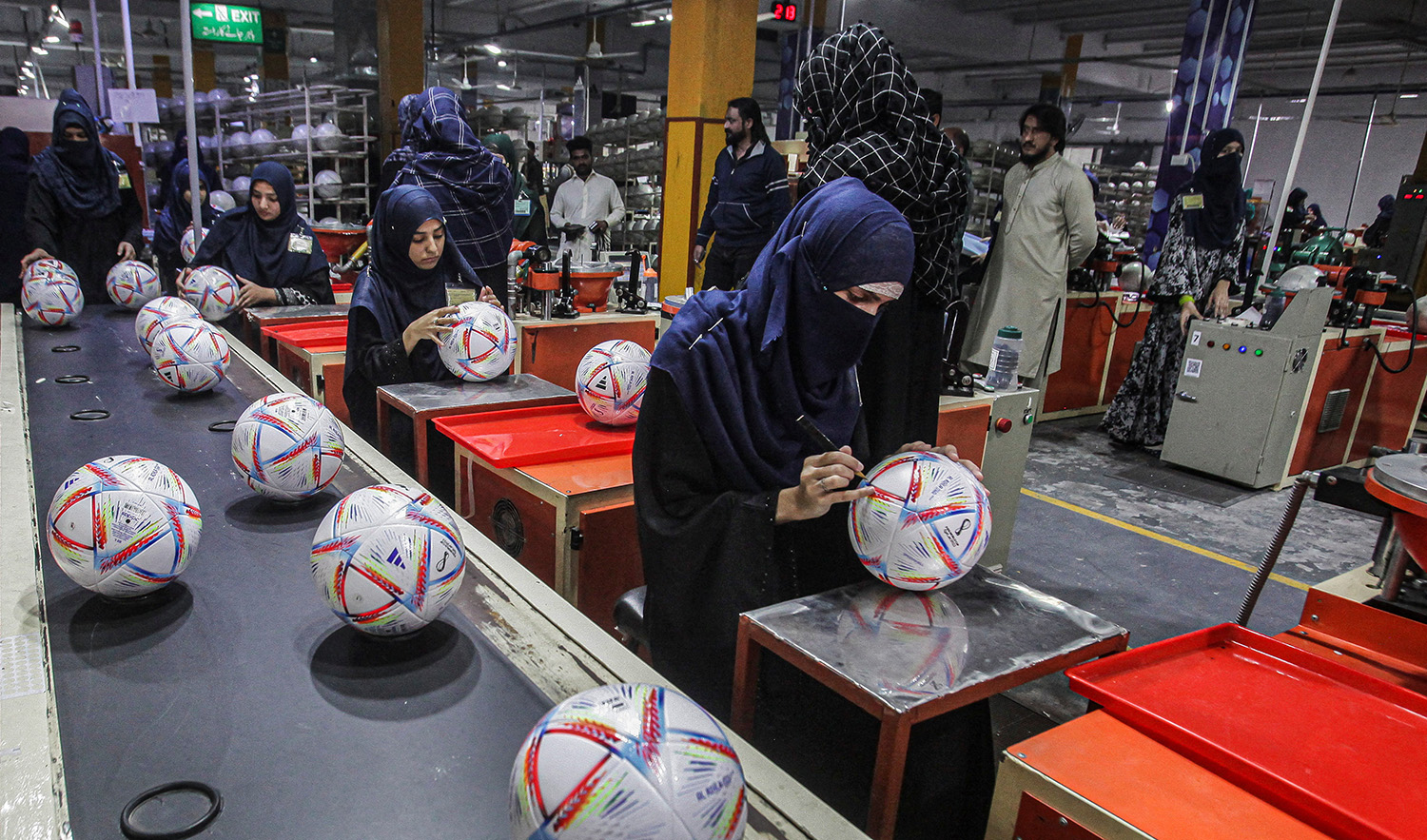 Workers conduct the final check to fix any cavity in the seams of balls inside the soccer ball factory in Sialkot, Pakistan on December 2, 2022. (REUTERS)