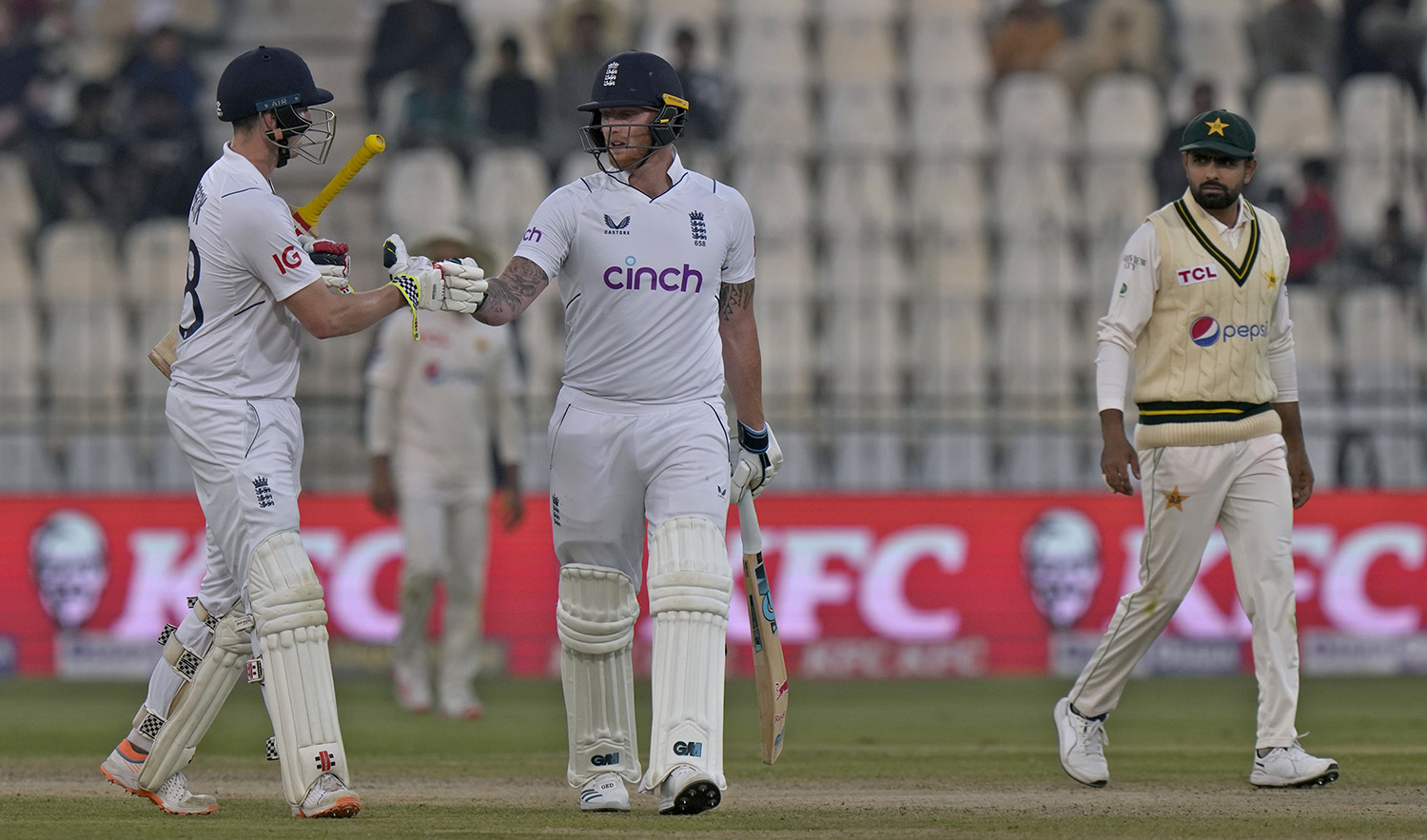 England's Harry Brook, left, bumps his fist with Ben Stokes, center, as Pakistan's Babar Azam watches during the second day of the second test cricket match in Multan, Pakistan, on December 10, 2022. (AP)