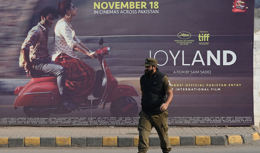 A cyclist rides past a promotional hoarding banner of Pakistan-produced movie "Joyland" displaying outside a cinema in Lahore on November 16, 2022. (AFP)